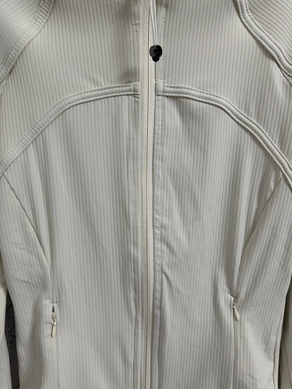Light cream ribbed jacket detail with full zipper and curved chest seam