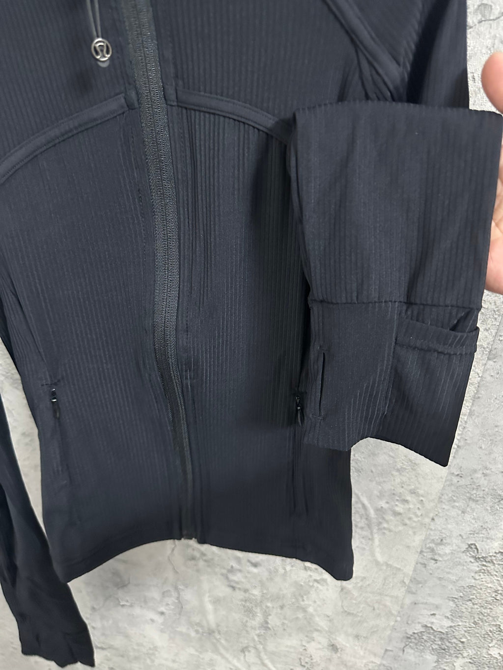 Dark jacket detail with pocket seams at hem and vertical zipper at center front