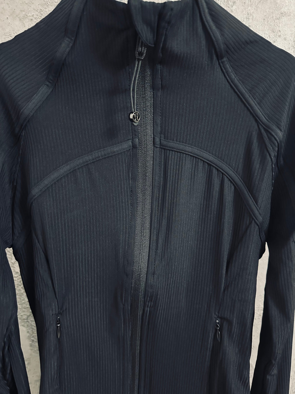 Dark high-neck zip jacket with curved paneling and front zipper details