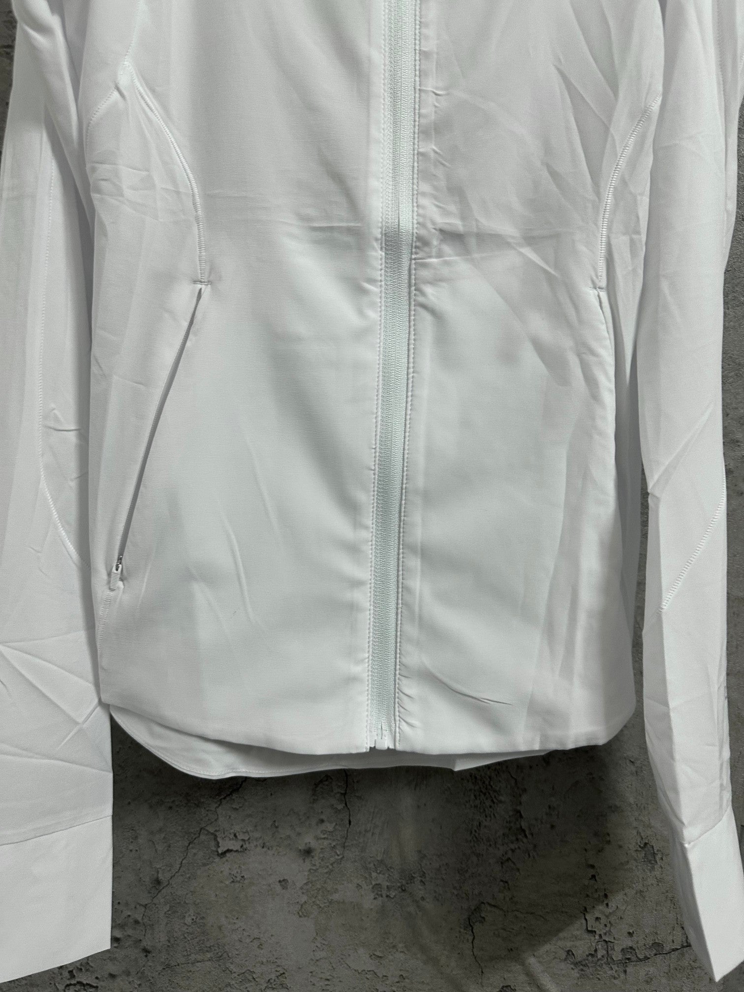 White zip-up jacket front with two side pockets and seam details
