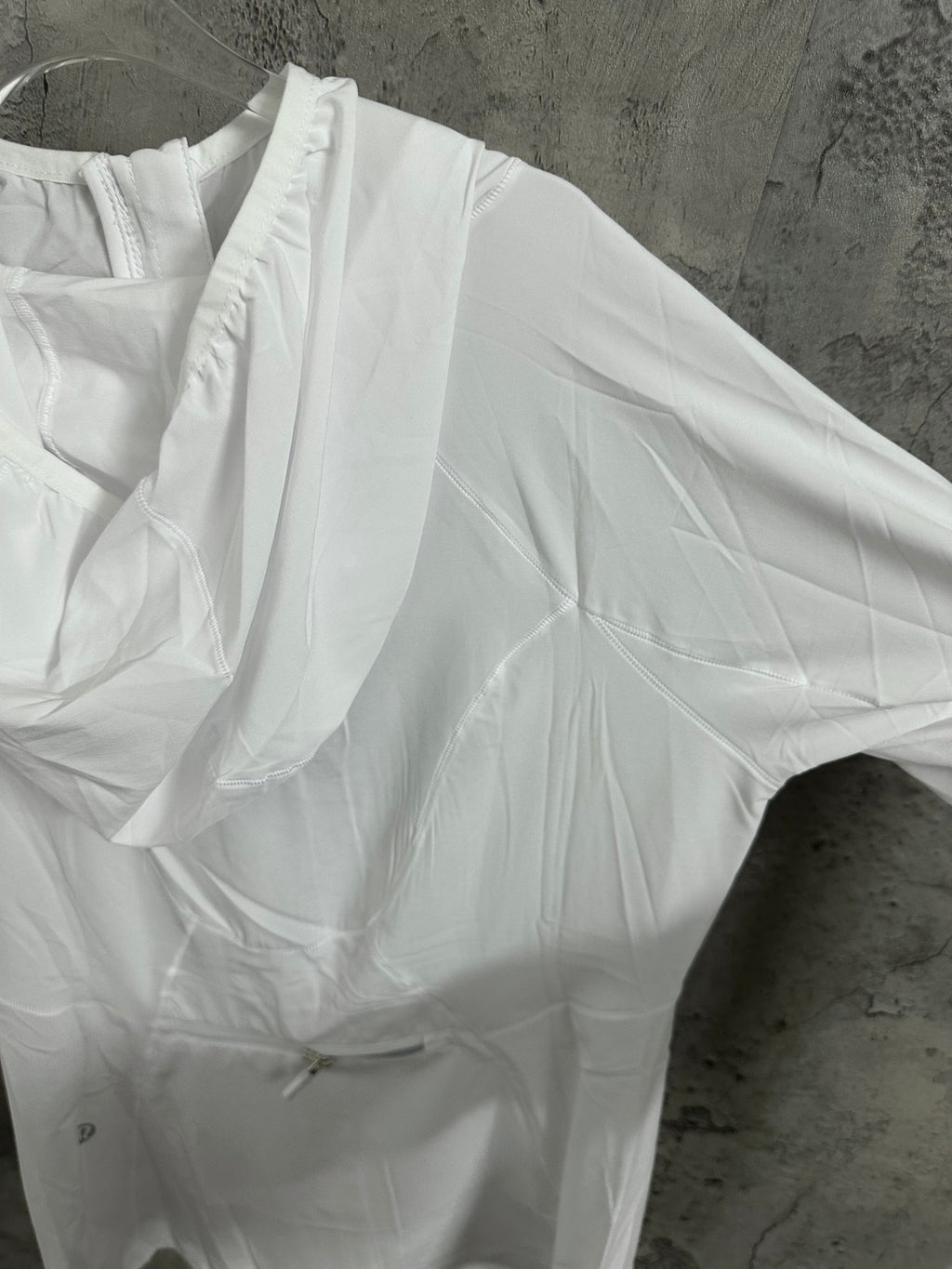 White hooded jacket with gathered shoulder and pleated front panel