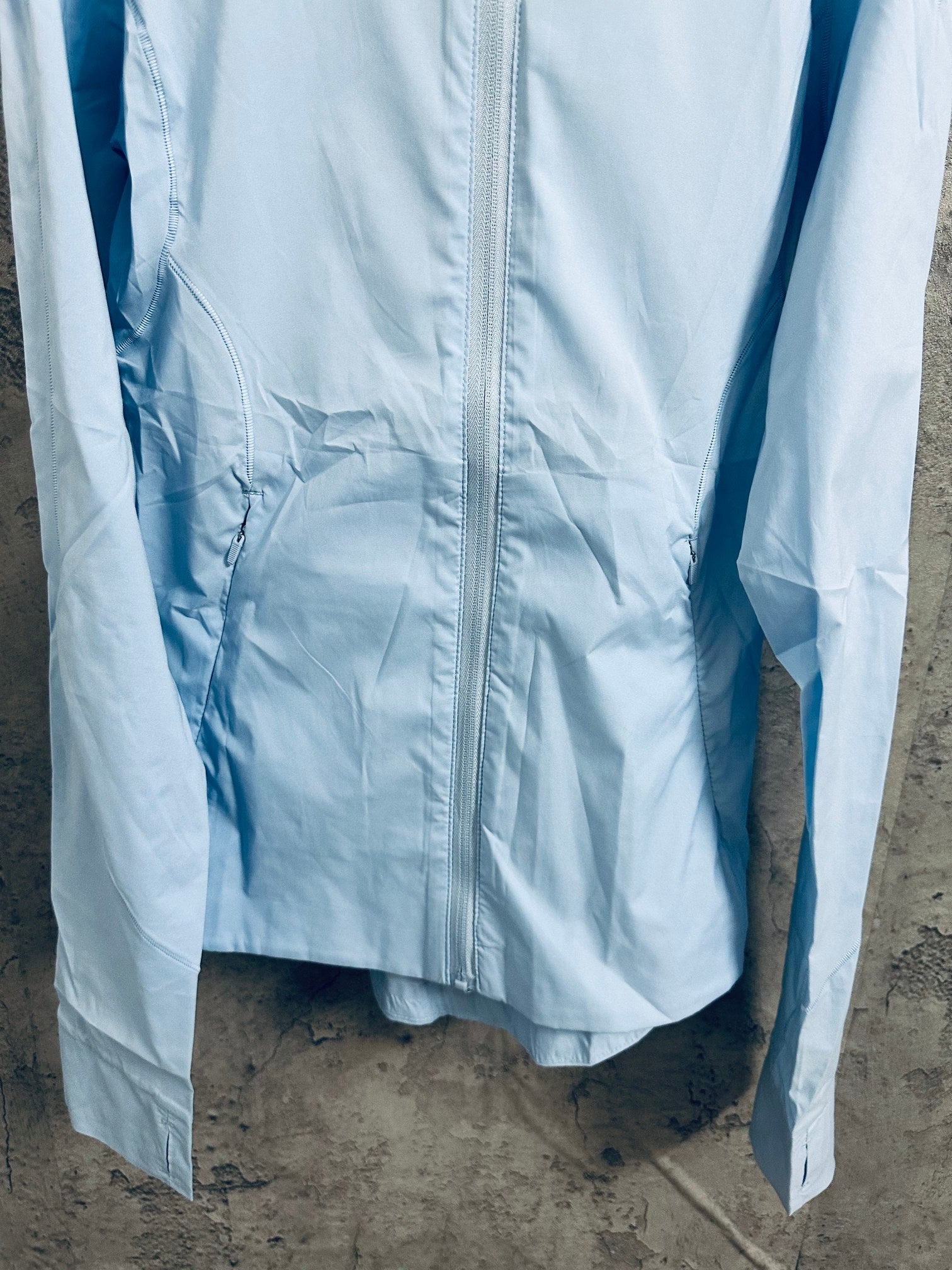 Light blue hooded windbreaker jacket, front view with ruched fabric detail