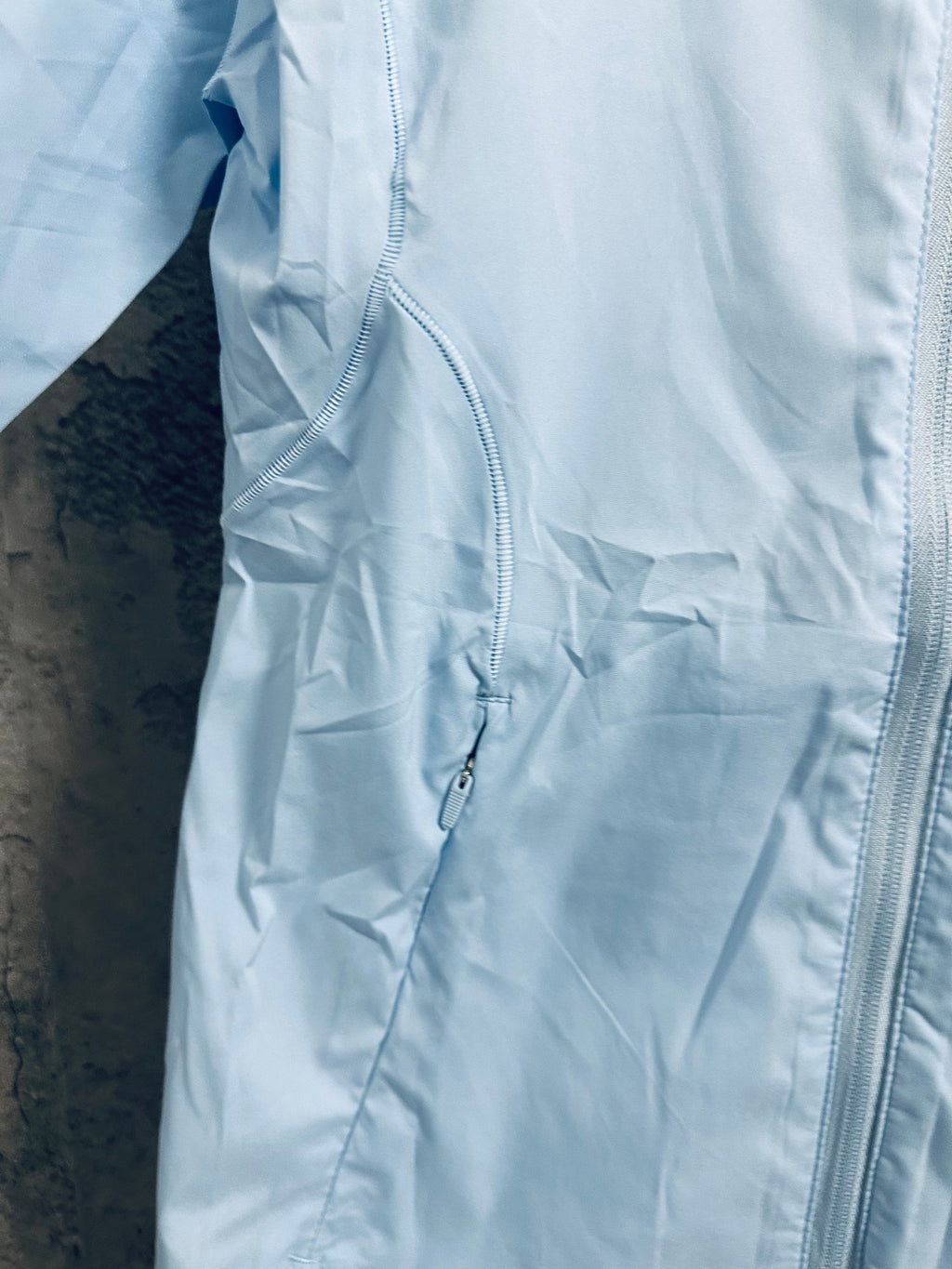 Light blue windbreaker jacket front pocket with zipper detail