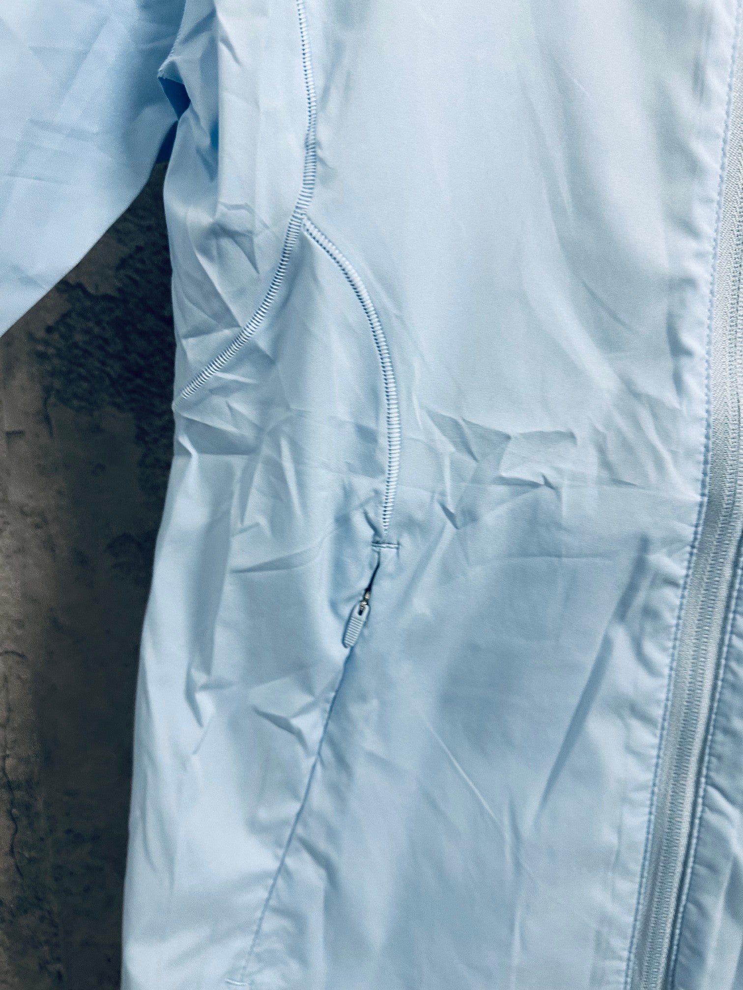 Light blue windbreaker jacket front pocket with zipper detail