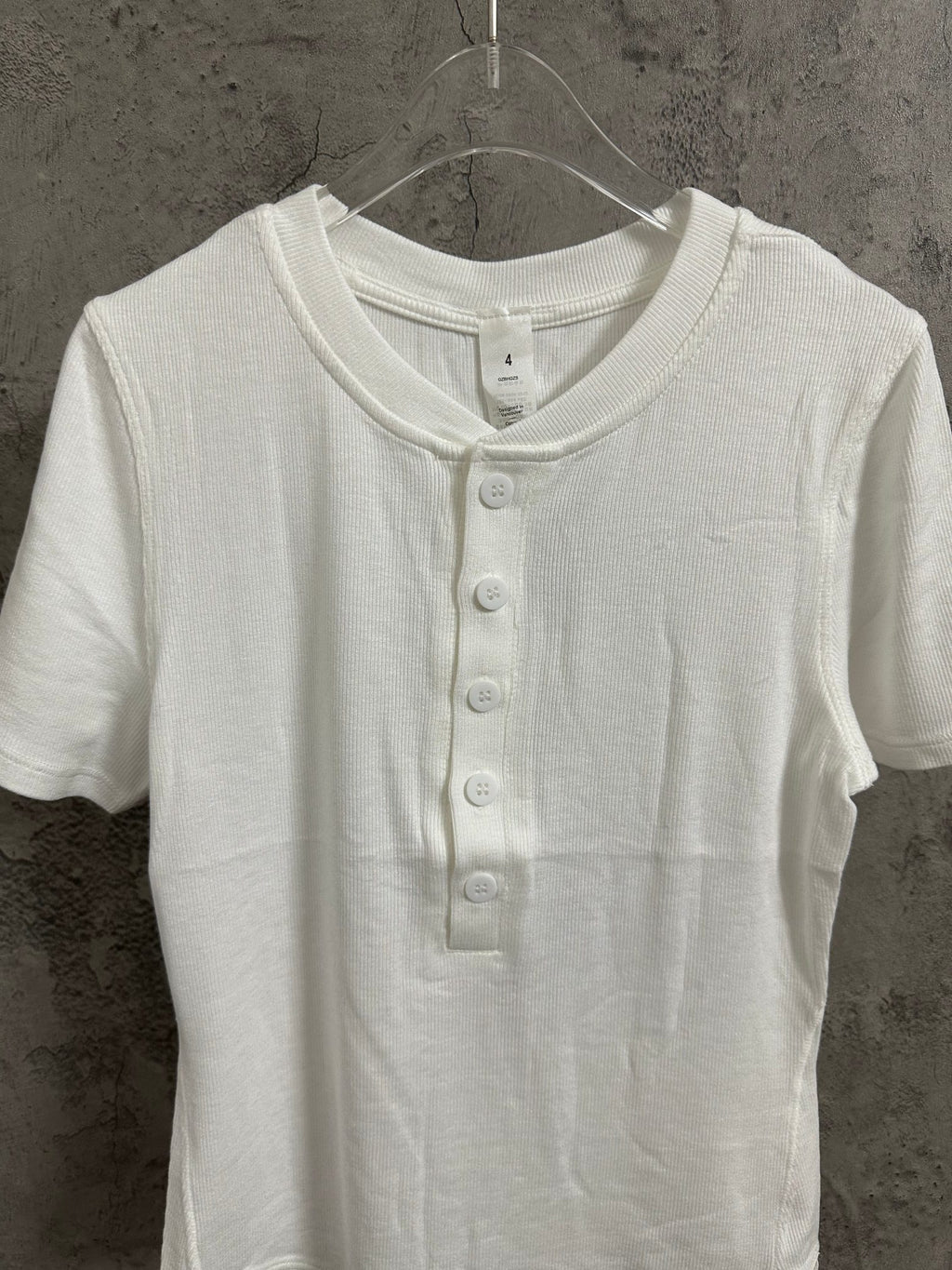 White henley T-shirt close-up showing ribbed collar and front buttons
