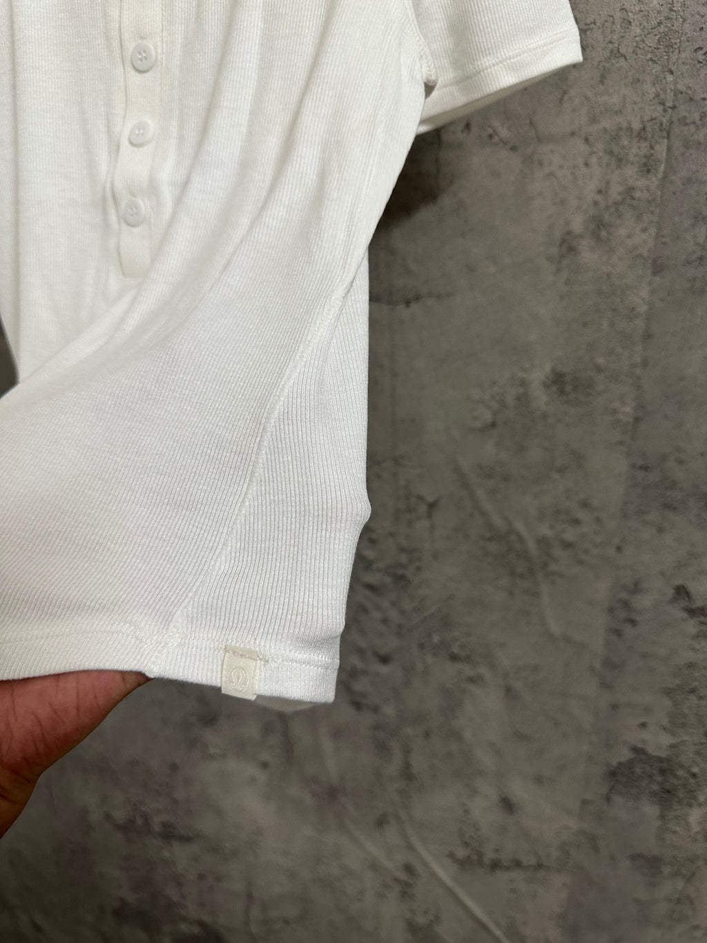 White henley T-shirt sleeve and button placket close-up