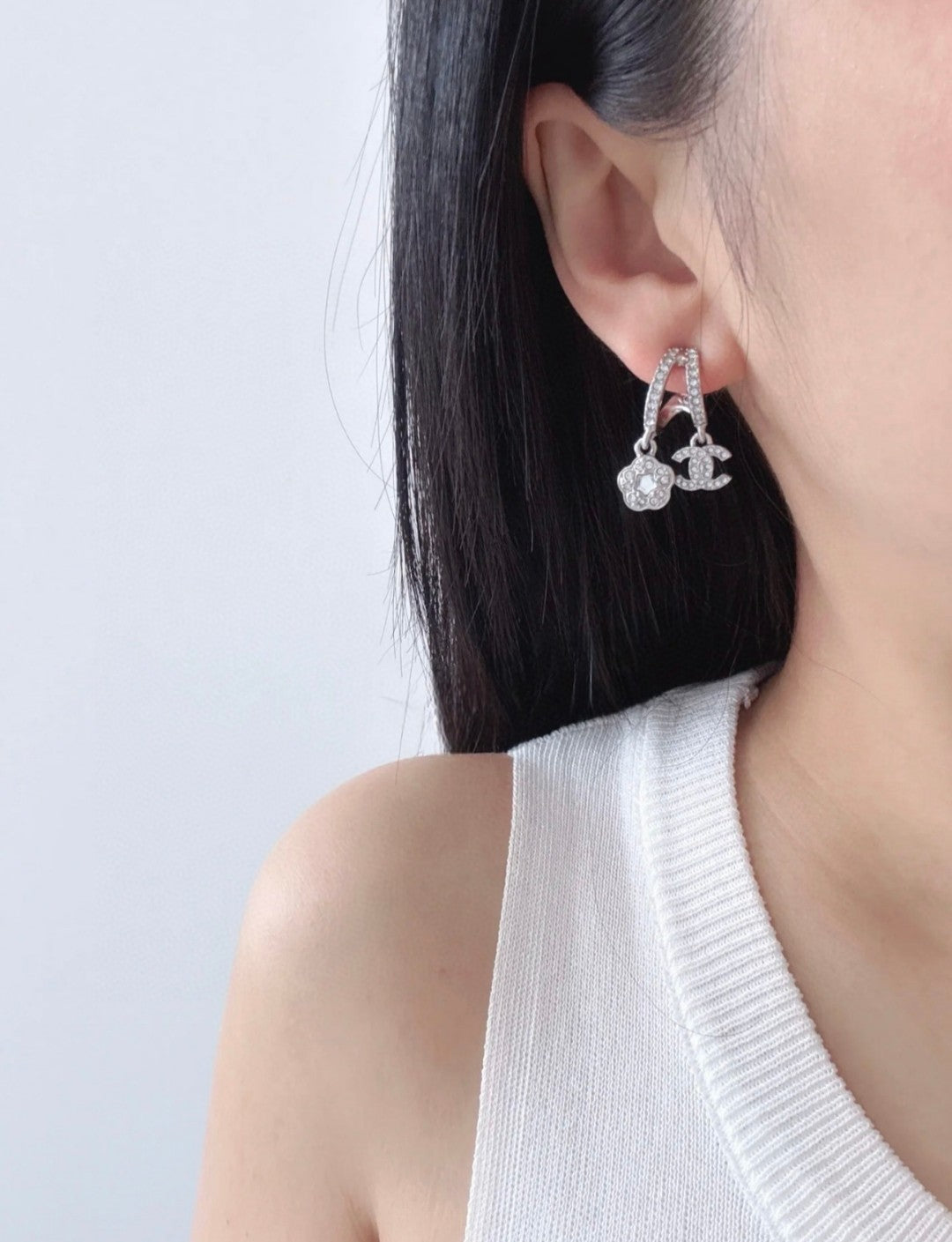 Hoop earrings with dangling charms, silver-tone, close-up on ear