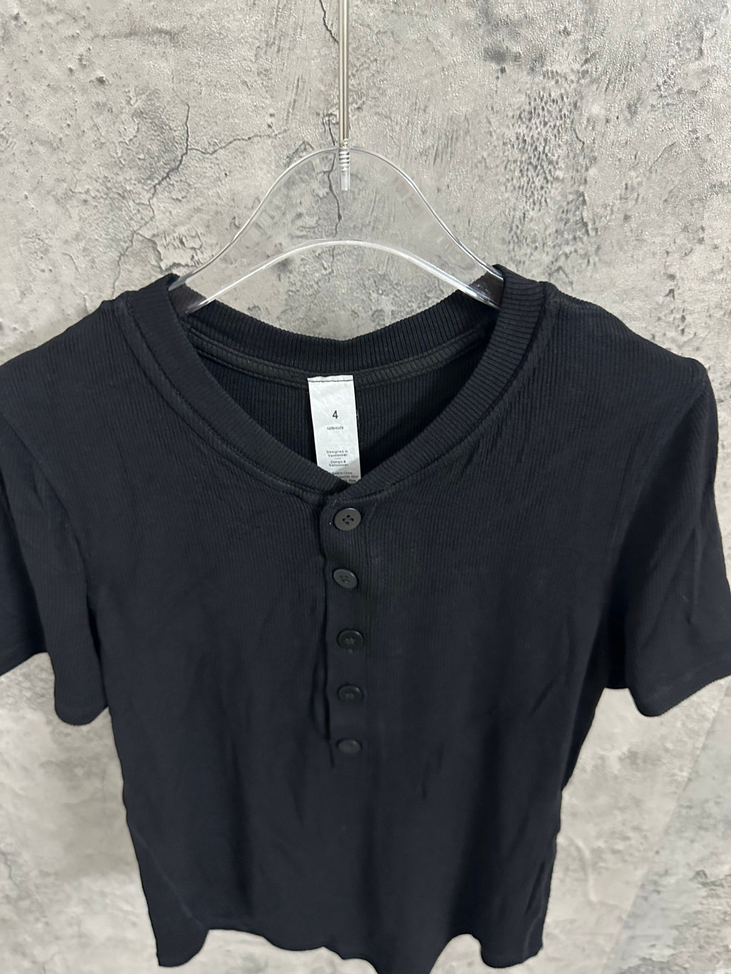Short-sleeve henley shirt neckline in dark knit, with V opening and dark buttons.