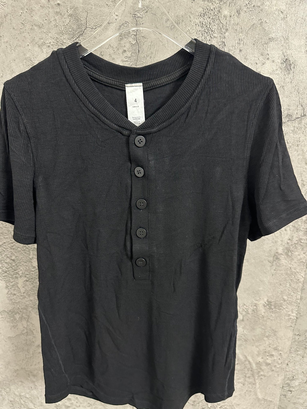 Short-sleeve henley shirt in dark knit fabric with V-neck opening and button placket.