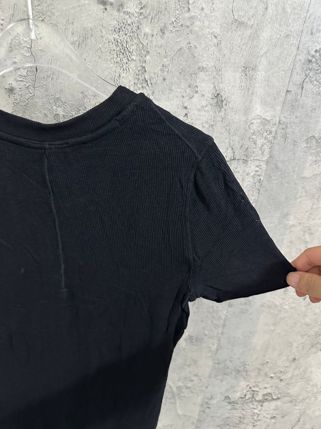 Side view of short-sleeve henley shirt in dark knit fabric with ribbed texture.