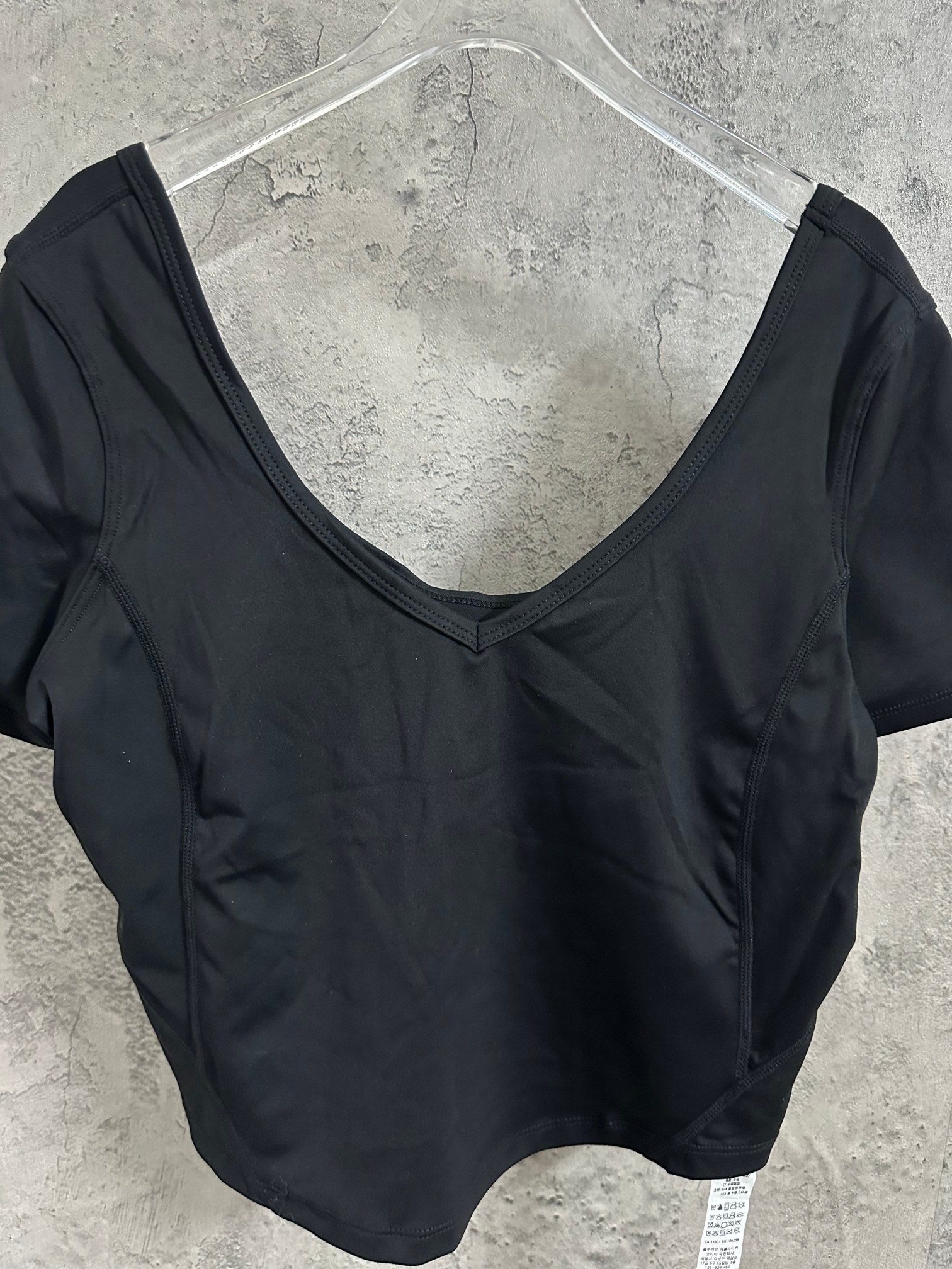Black V-neck cropped top with short sleeves, close-up on neckline