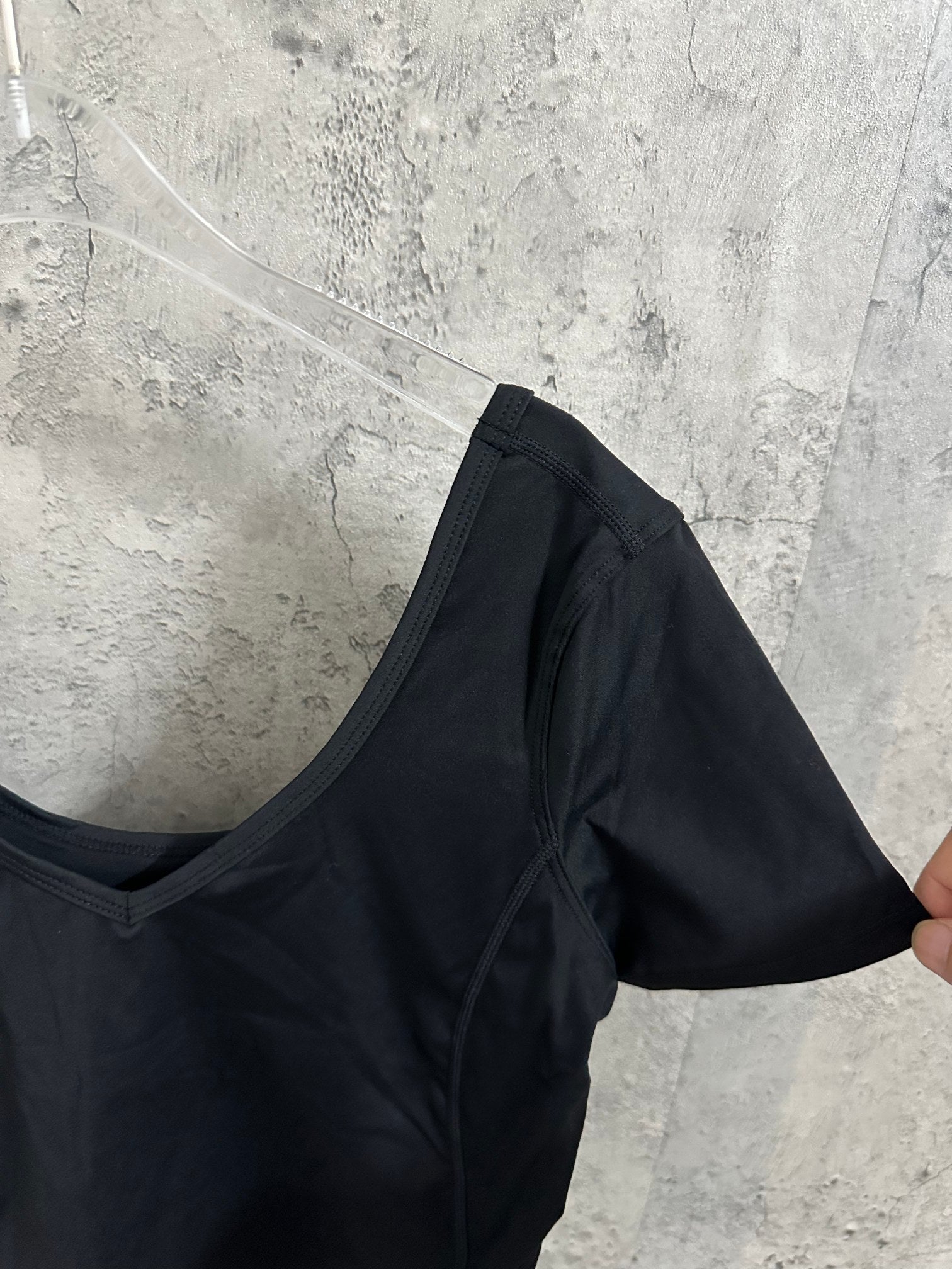 Black cropped top with V-neck and short sleeves, side view