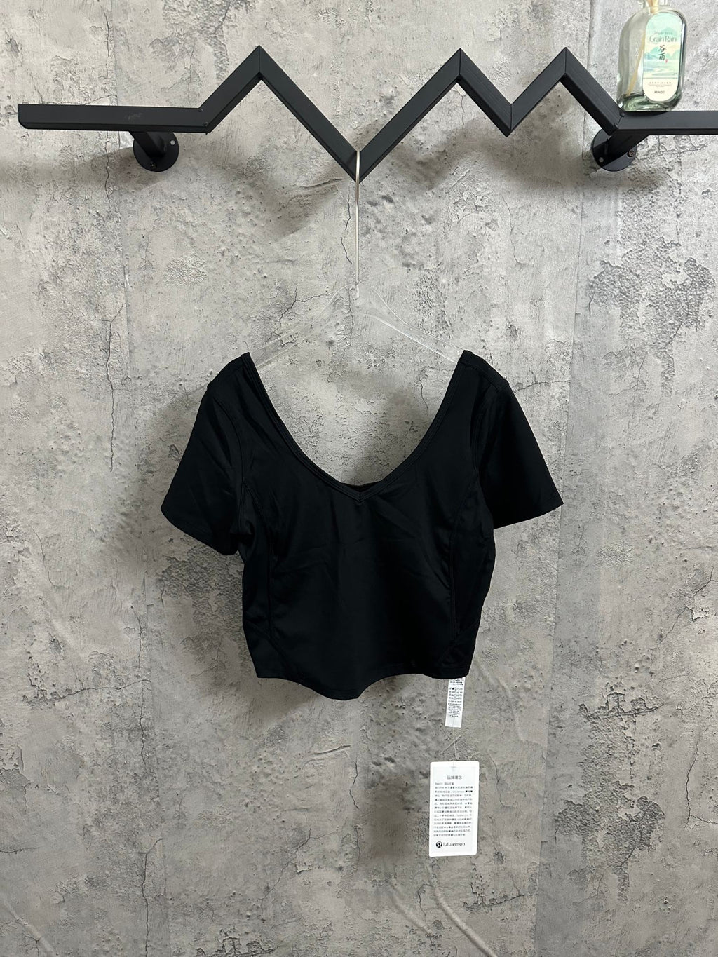 Black V-neck cropped top with short sleeves and hanging product tags