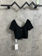 Black V-neck cropped top with short sleeves and small chest logo