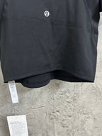 Black cropped top with small chest logo and product tags near hem