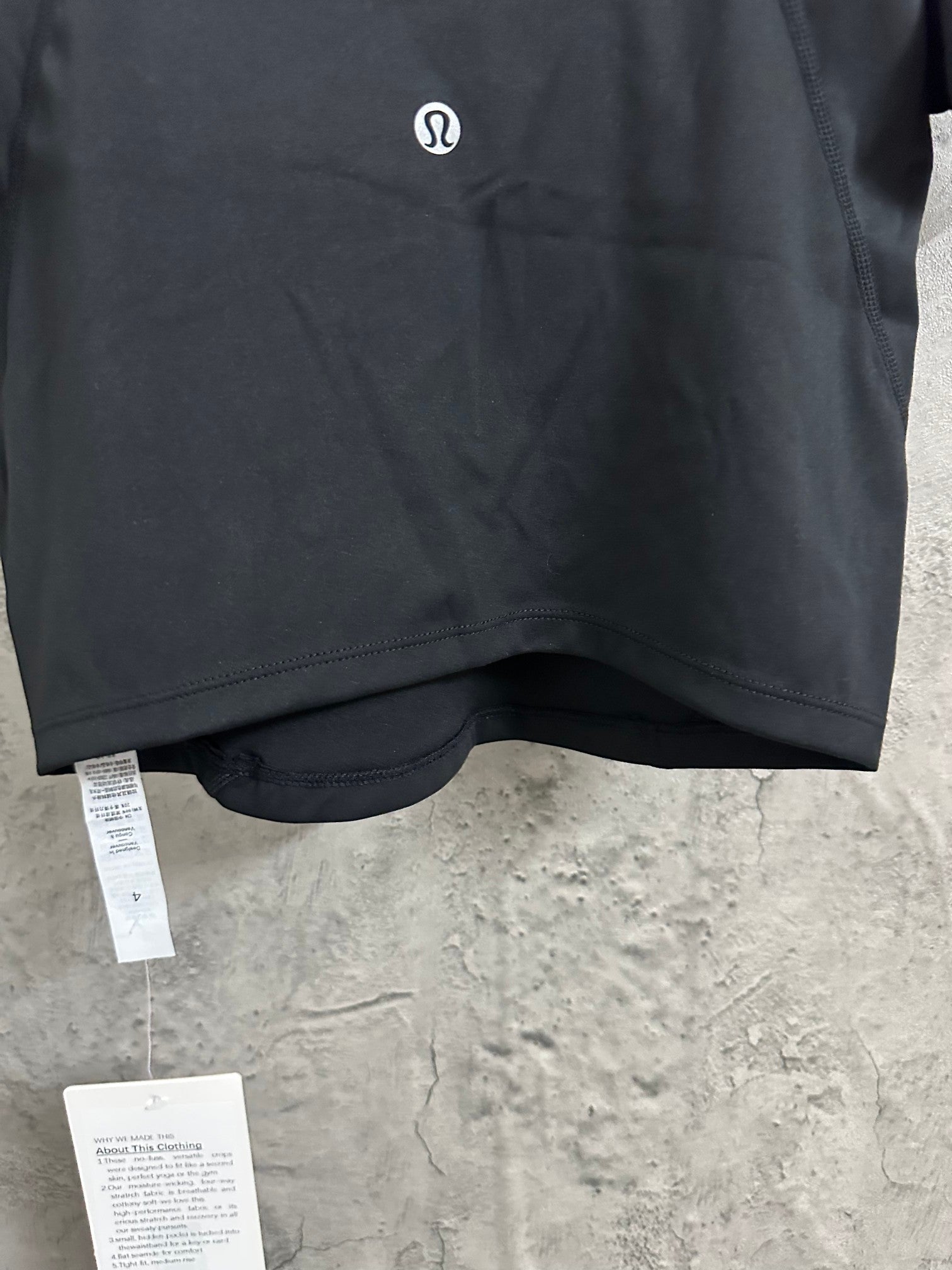 Black cropped top with small chest logo and product tags near hem