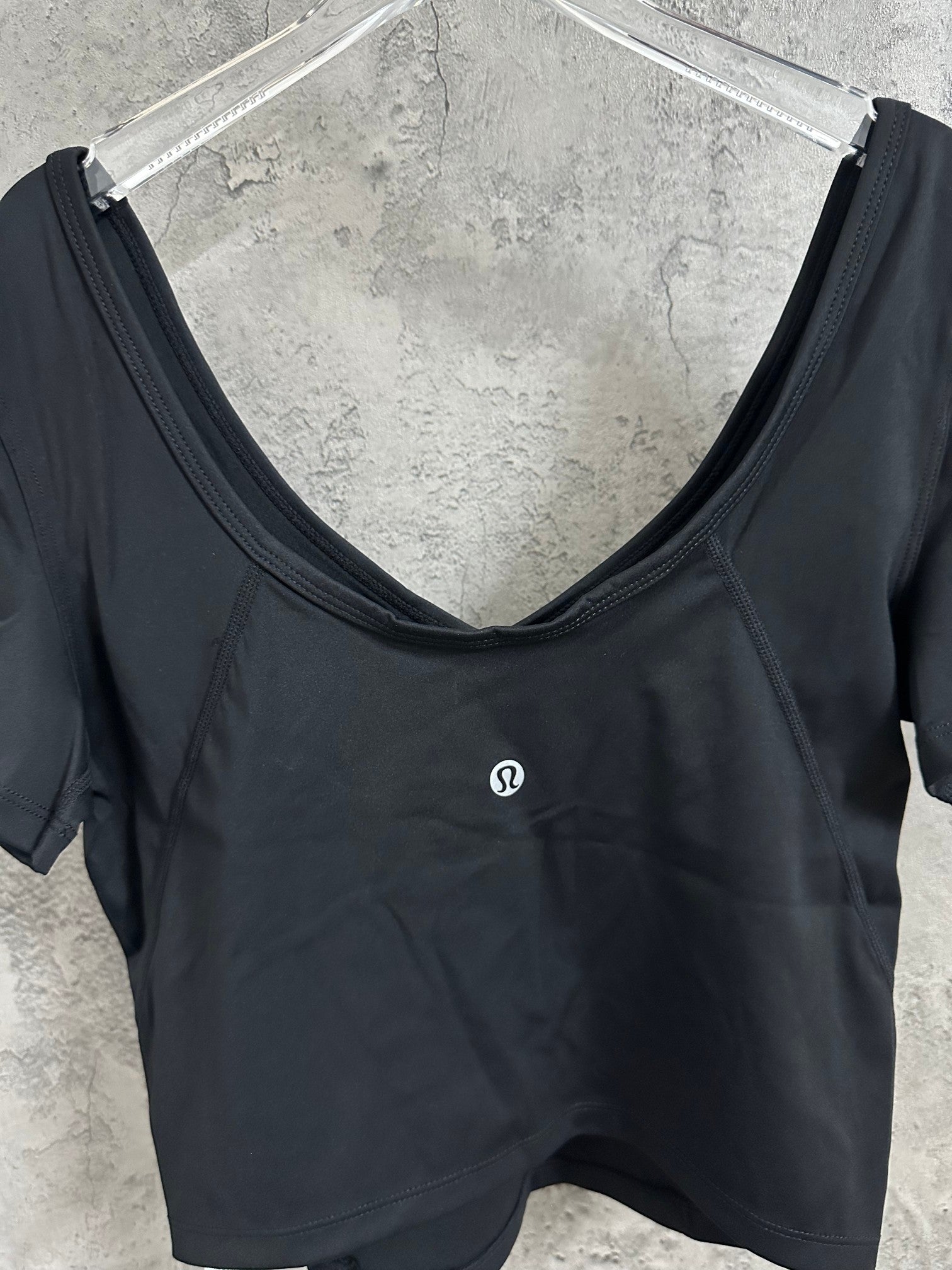 Black V-neck cropped top with short sleeves and small chest logo