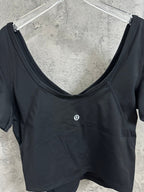 Women’s dark athletic crop top, close-up of scoop neck and small chest logo