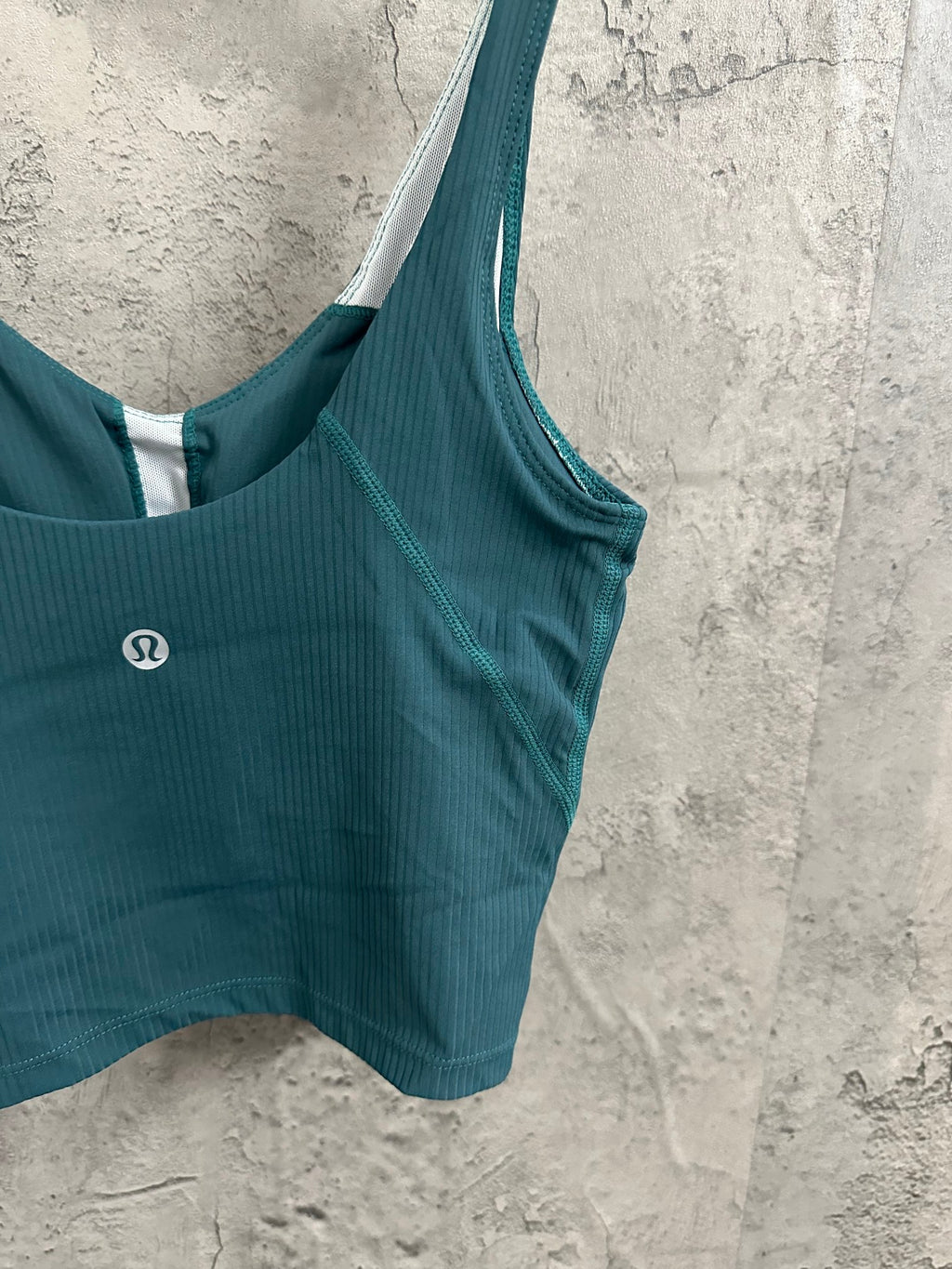 Teal bralette with wide straps and oval chest logo, scoop neckline