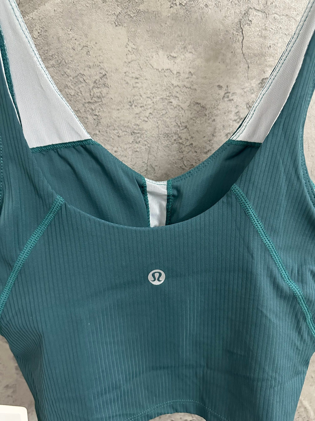 Teal ribbed camisole with scoop neckline and white-trimmed armholes; small logo