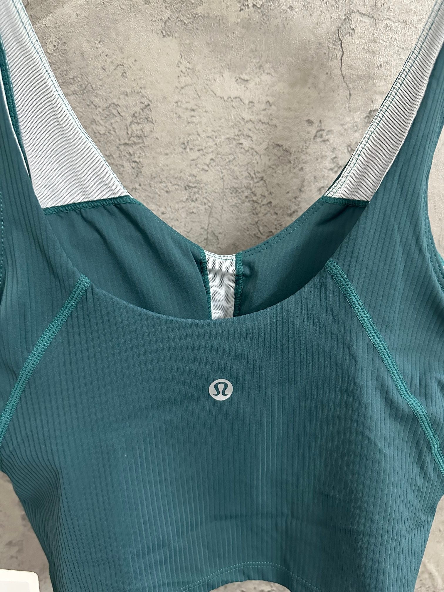 Teal ribbed camisole with scoop neckline and white-trimmed armholes; small logo
