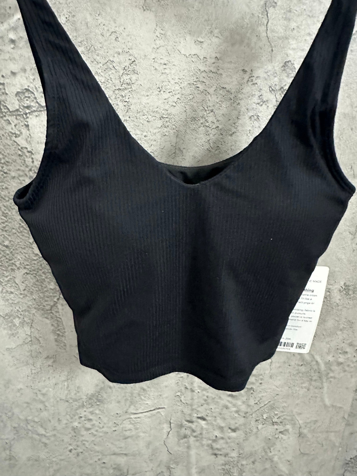 Black ribbed sports bra close-up of scoop neckline and shoulder straps