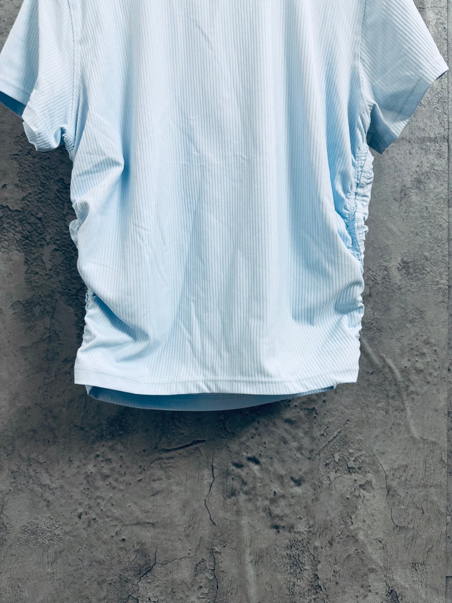 Light blue T-shirt back view on hanger, short sleeves and ribbed fabric