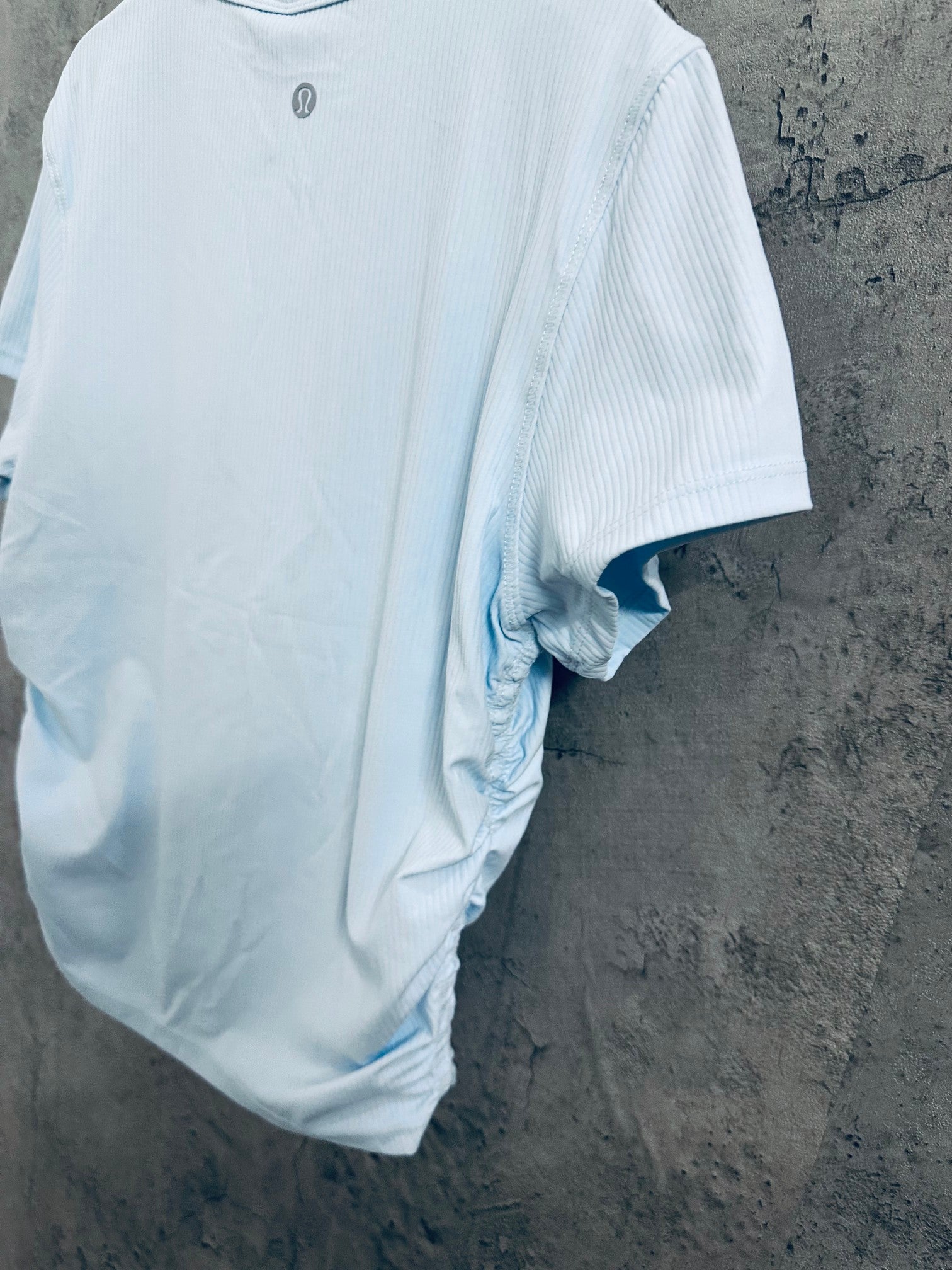 Light blue crew-neck T-shirt back view with small chest logo, on hanger