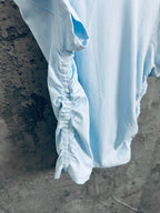 Light blue ribbed T-shirt viewed from side, showing sleeve and drape