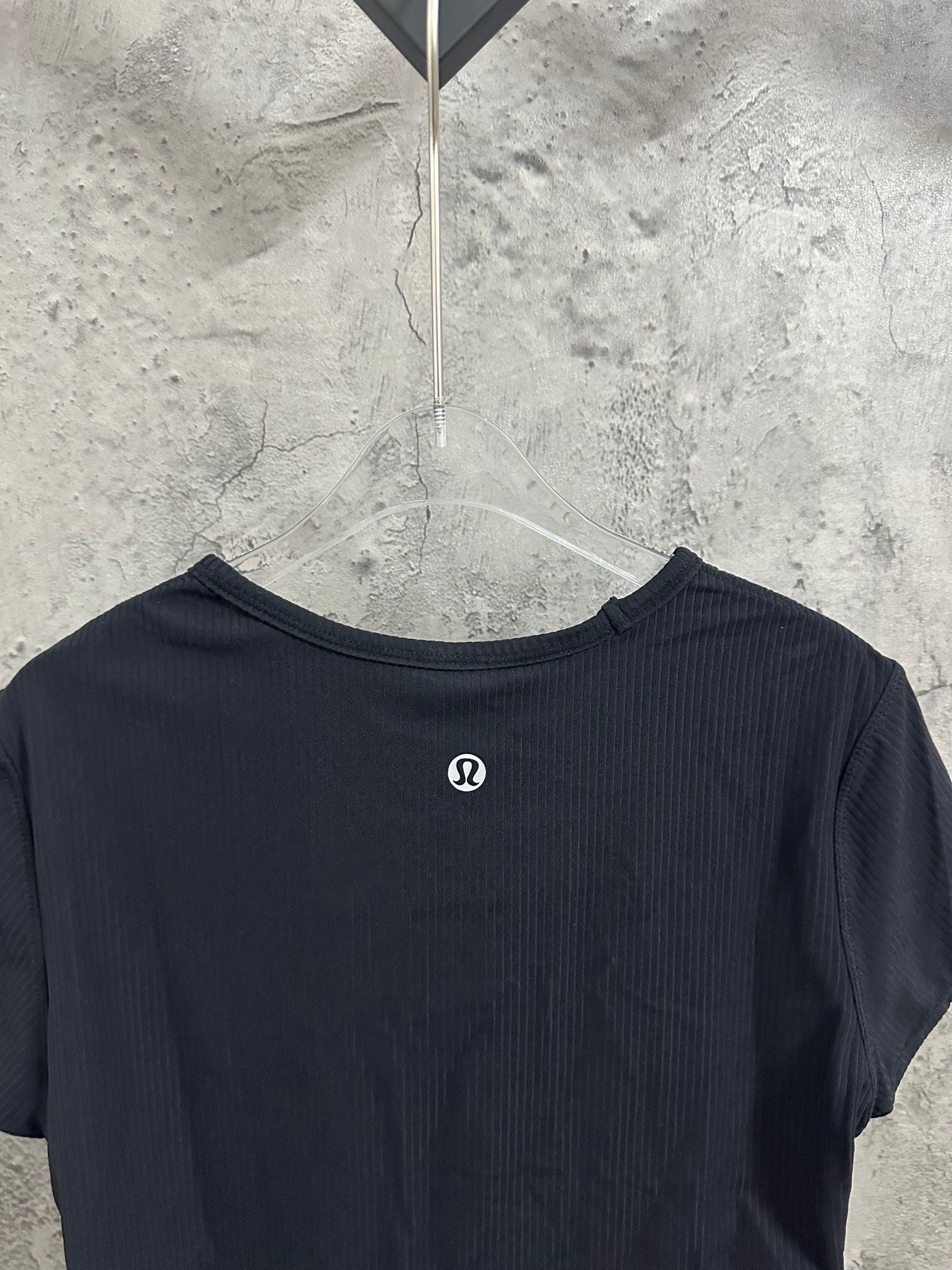 Dark navy T-shirt back view with small round emblem near upper back