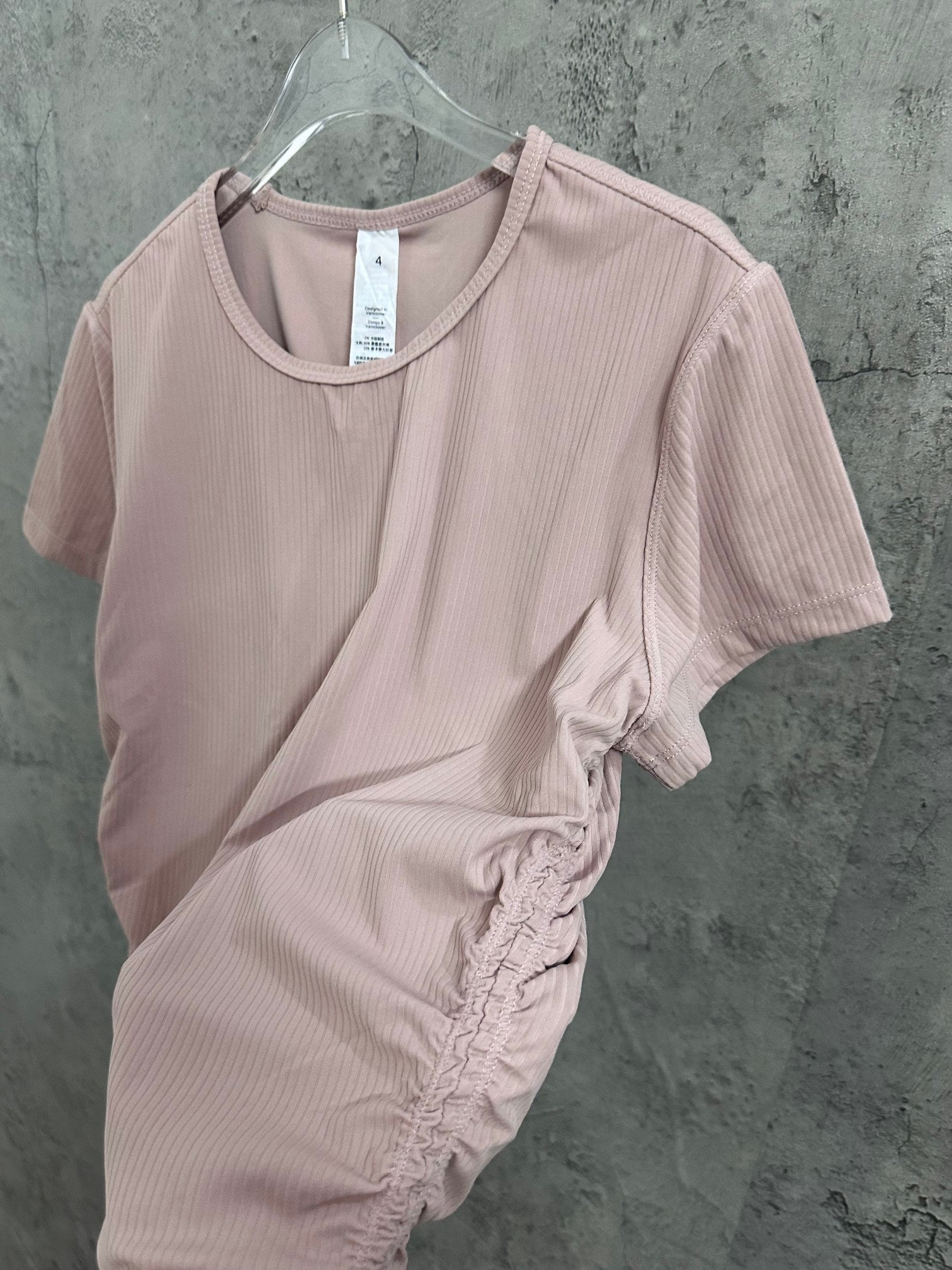 Light pink ribbed T-shirt on hanger with side twist