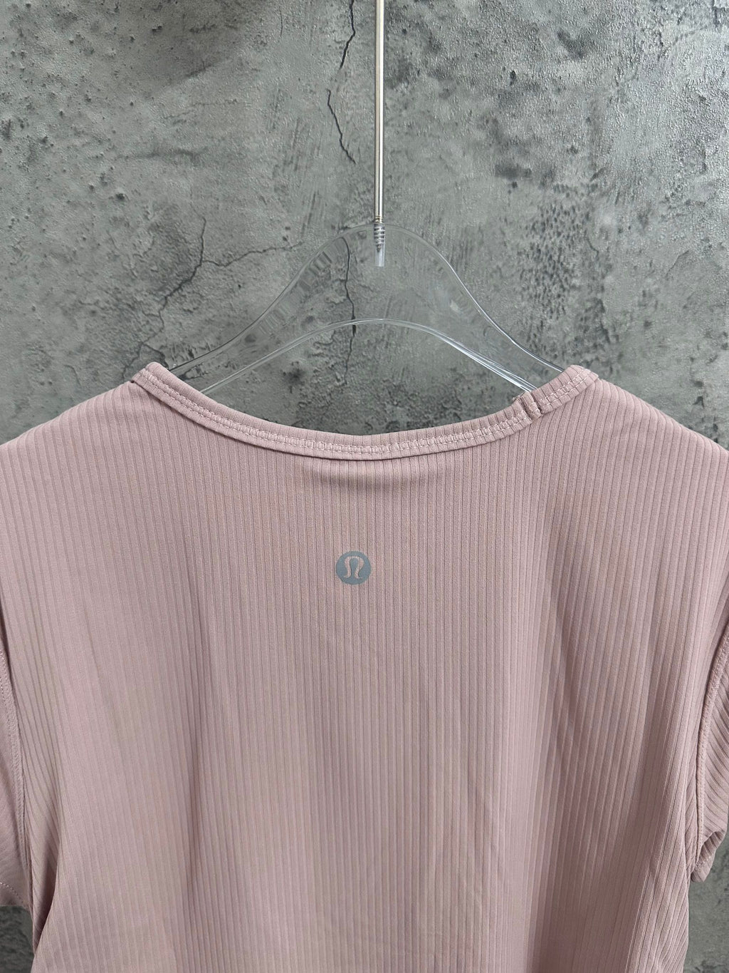 Light pink T-shirt neckline with small circular logo on upper back panel.