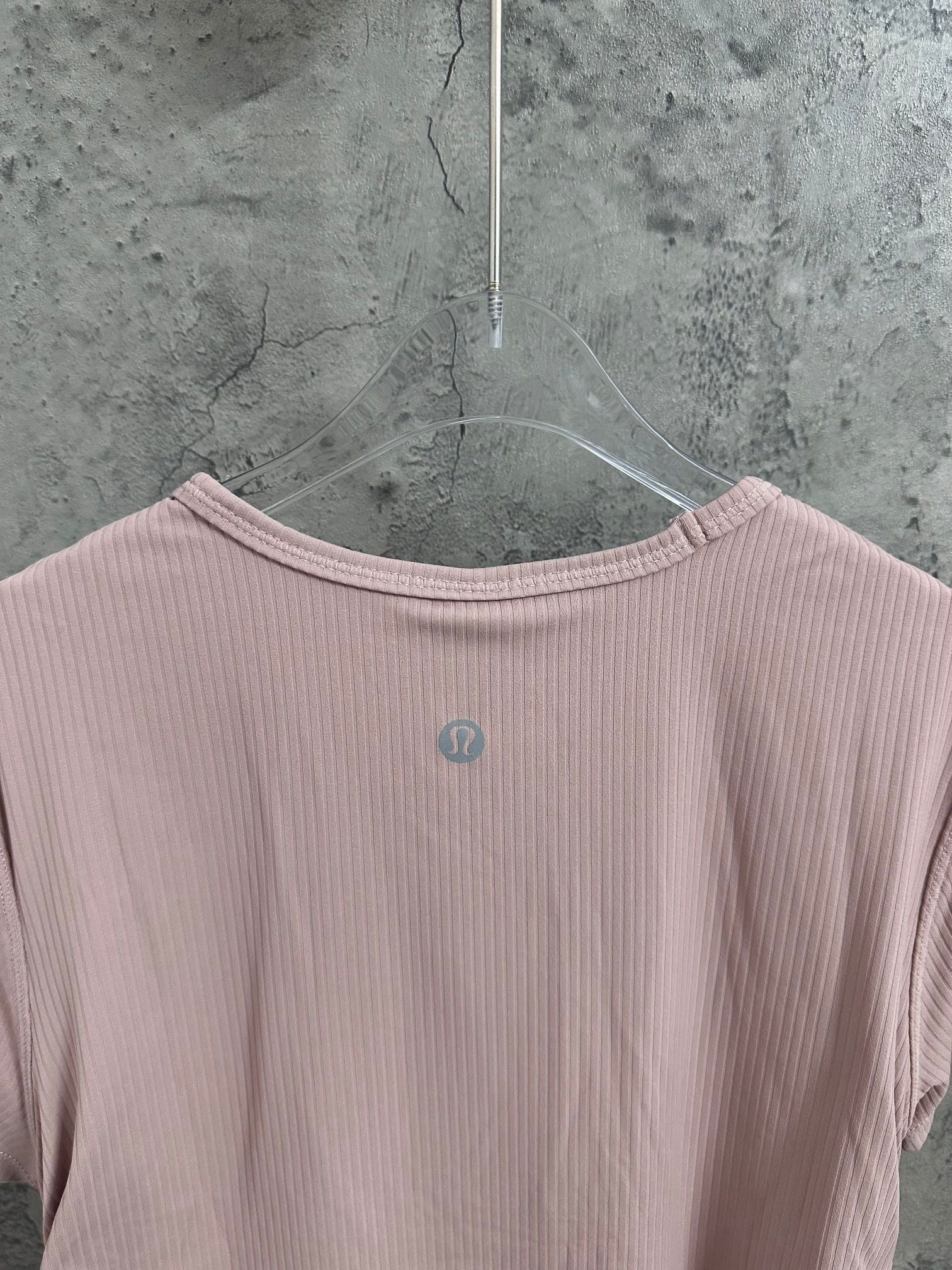 Light pink T-shirt neckline with small circular logo on upper back panel.