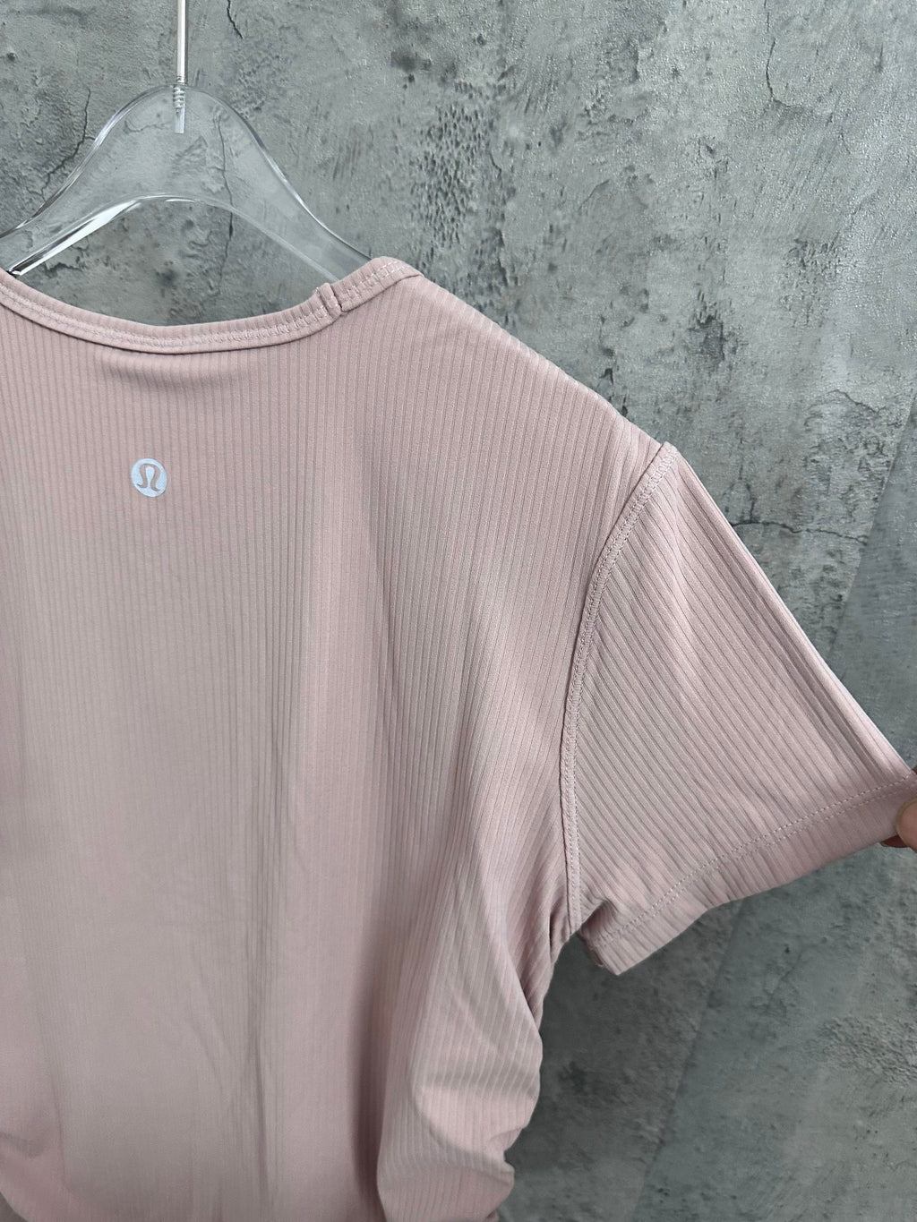 Light pink crewneck T-shirt sleeve and back panel with vertical ribbed texture.