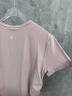 Light pink crewneck T-shirt sleeve and back panel with vertical ribbed texture.