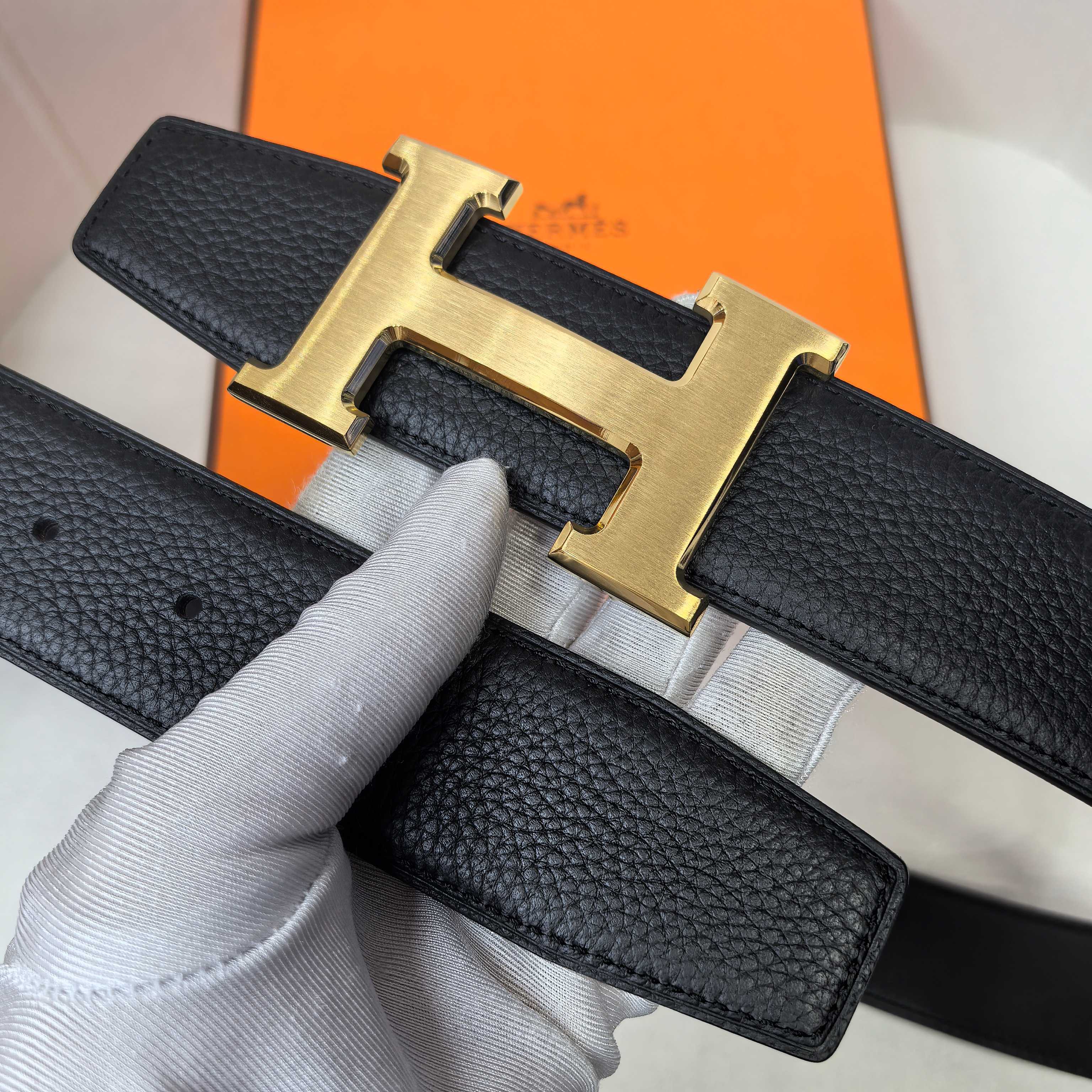 Hermes belt close-up, black textured leather with gold-tone H buckle