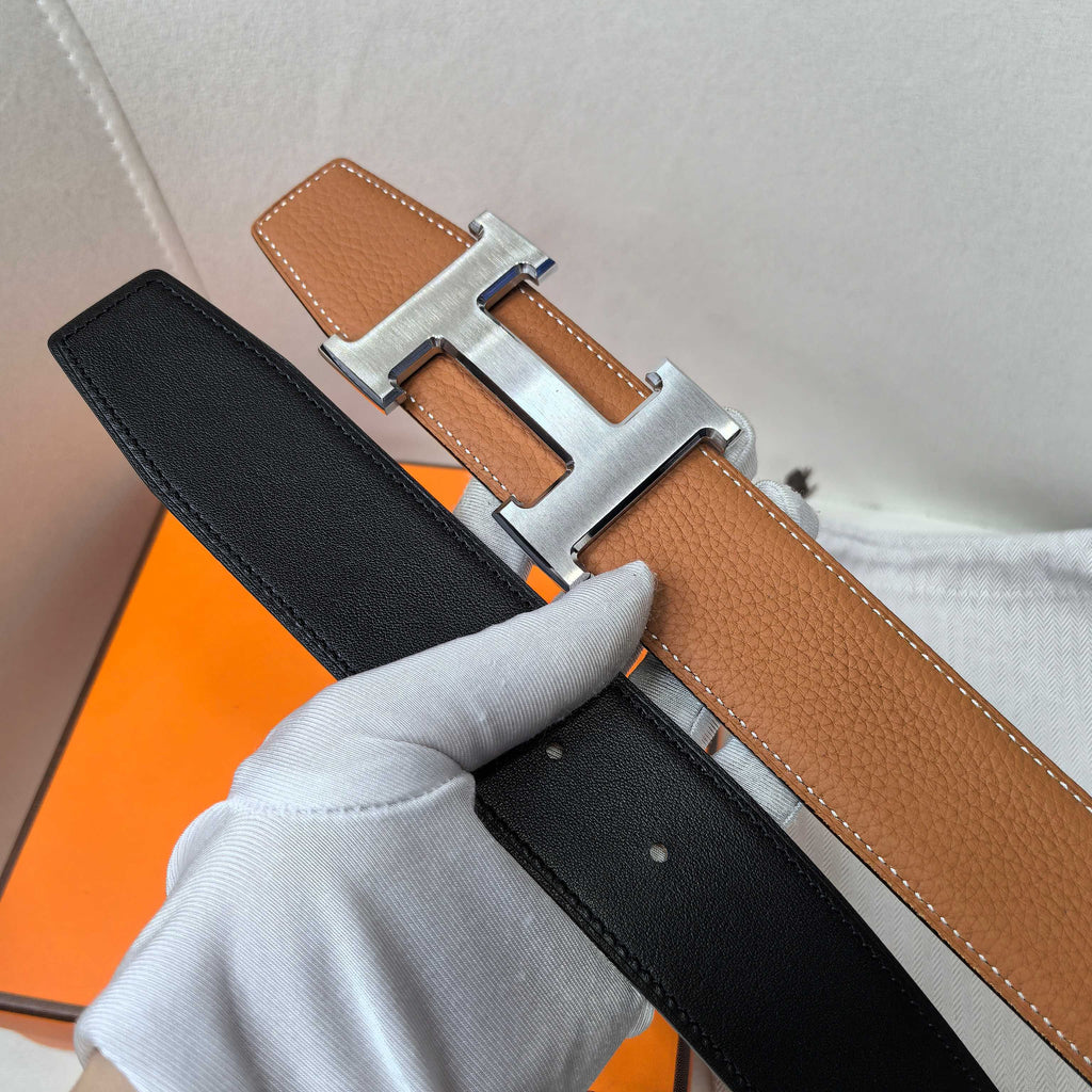 Hermes reversible belt showing black side and tan-brown front with silver-tone buckle