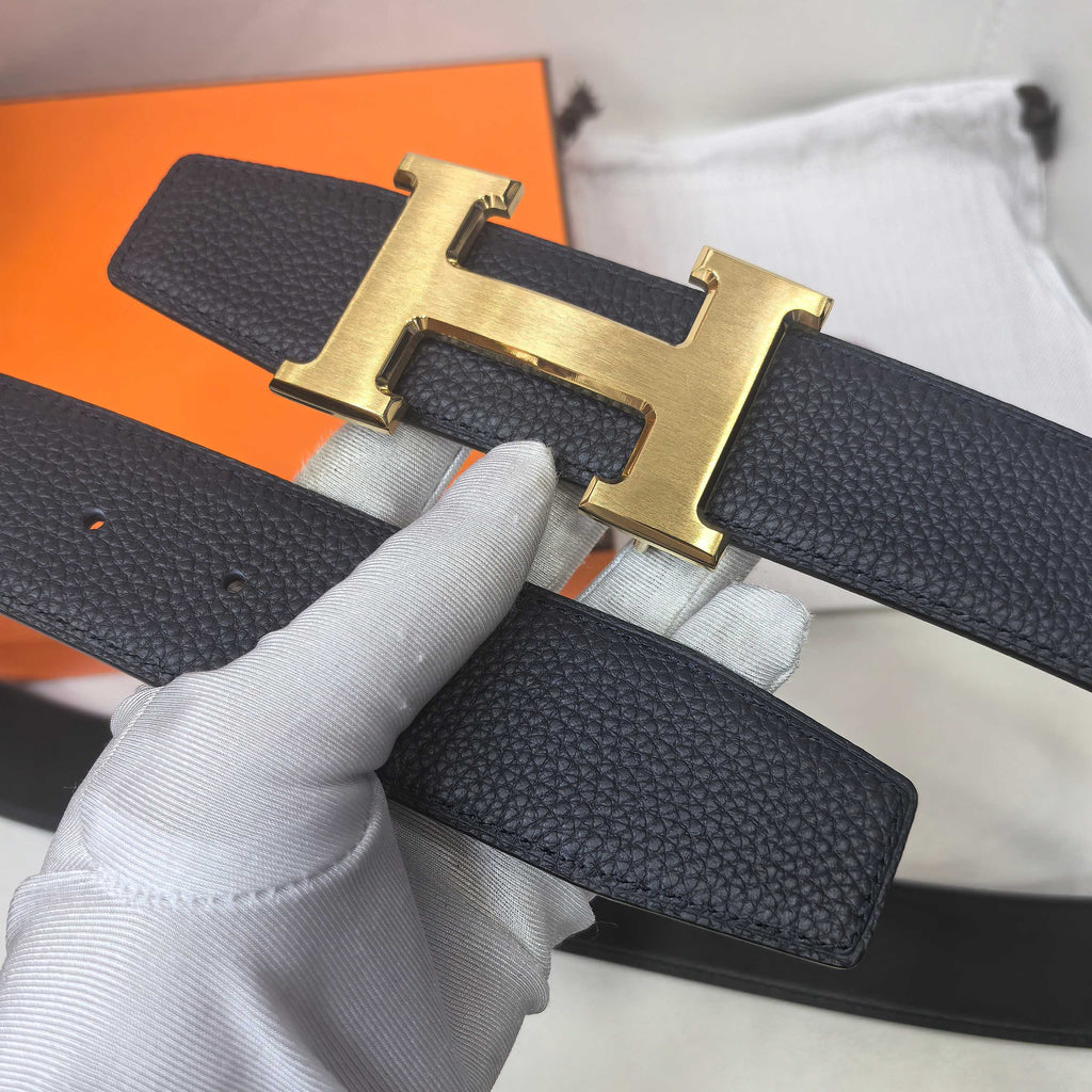 Hermes belt buckle view: dark leather strap with gold-tone H and stitched holes