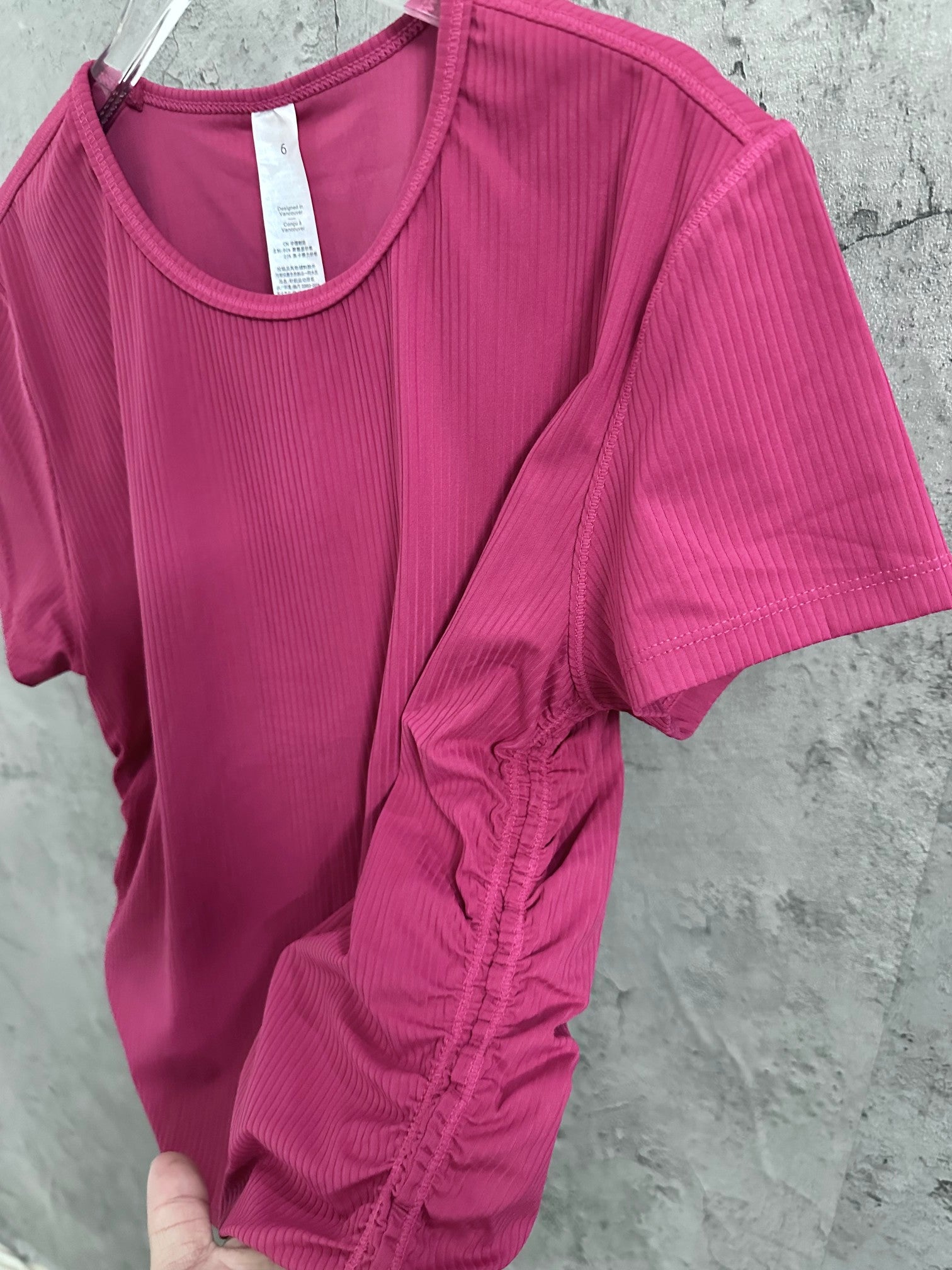 Pink ribbed crewneck short-sleeve top with gathered ruching at the lower hem