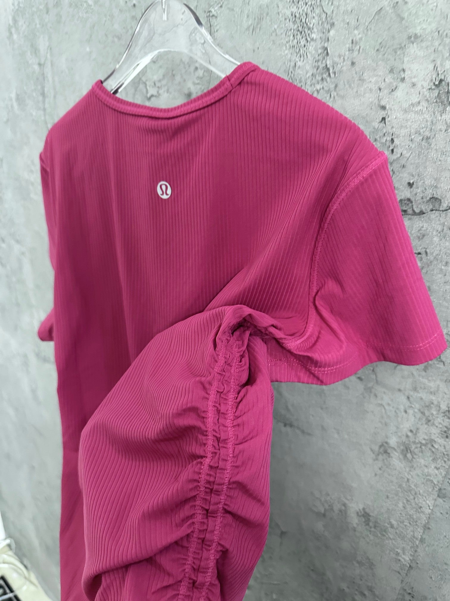 Pink ribbed T-shirt back view with circular logo and short sleeves
