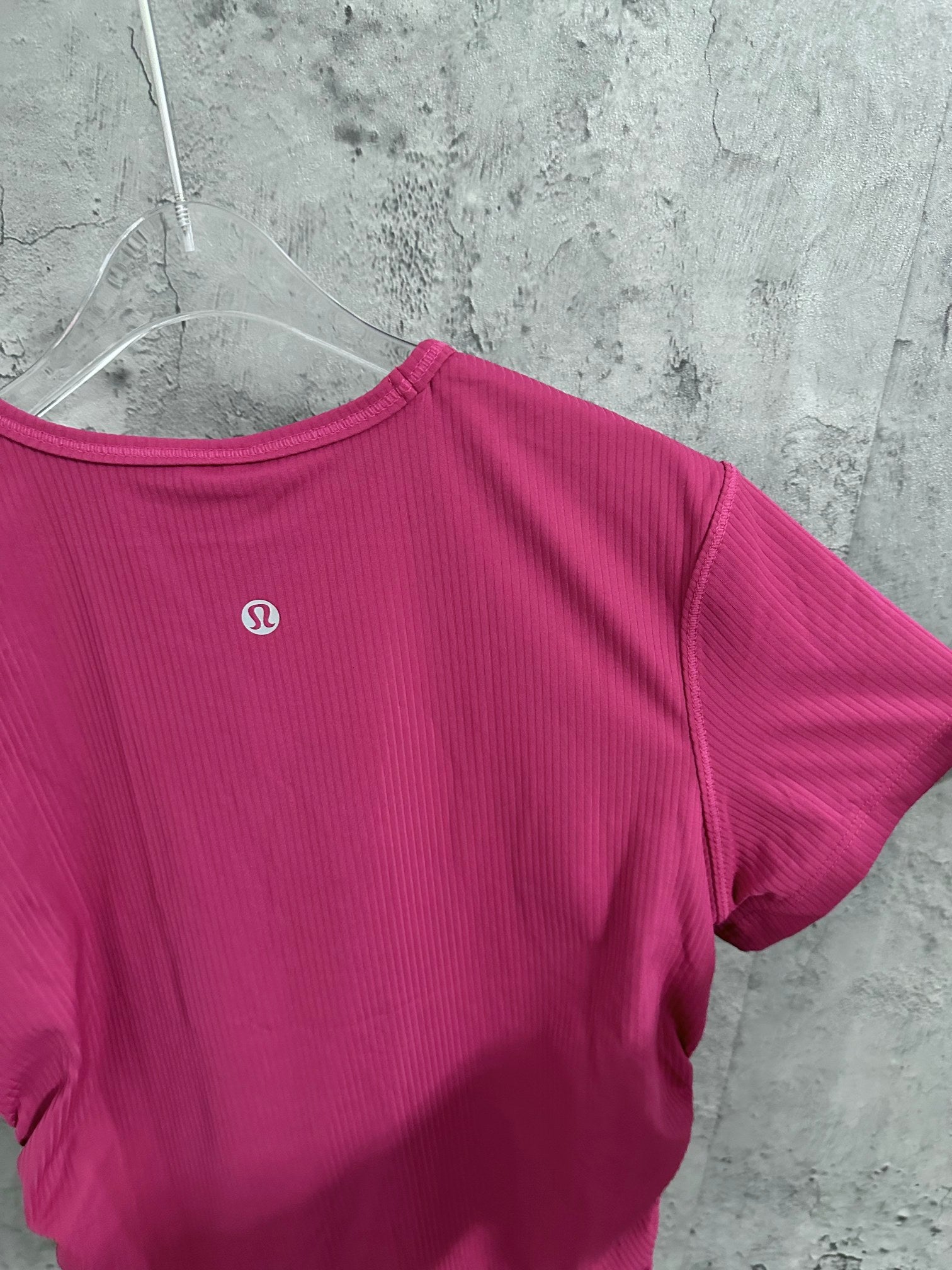 Pink ribbed T-shirt back with small circular logo near upper chest