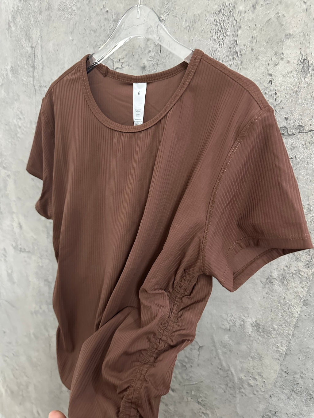 Brown ribbed crewneck T-shirt with draped front on hanger