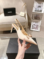 Women's beige pointed-toe slingback heel with bow and block heel, held in hand