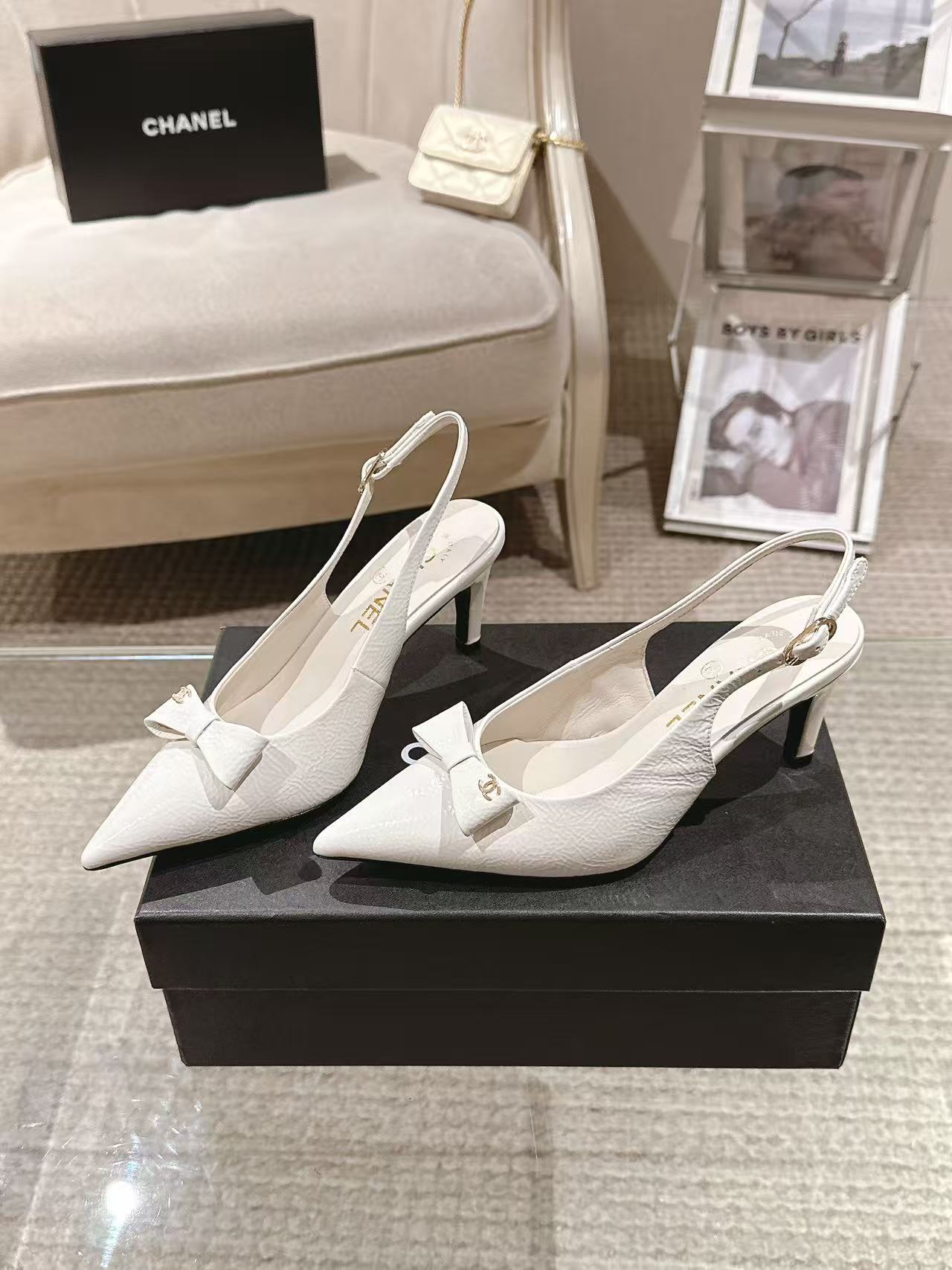 White pointed-toe slingback pumps with bow detail and slim black heel