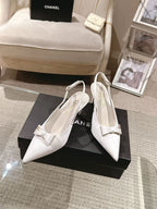 Chanel ladies white pointed-toe slingback pumps on black box, angled pair view