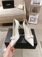 White pointed-toe slingback heels with bow strap, angled side view