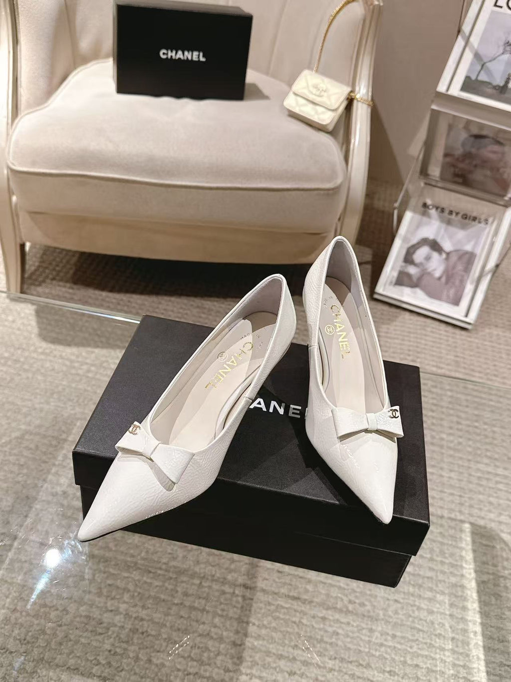 White pointed-toe slingback heels, viewed from the front with bow strap detail
