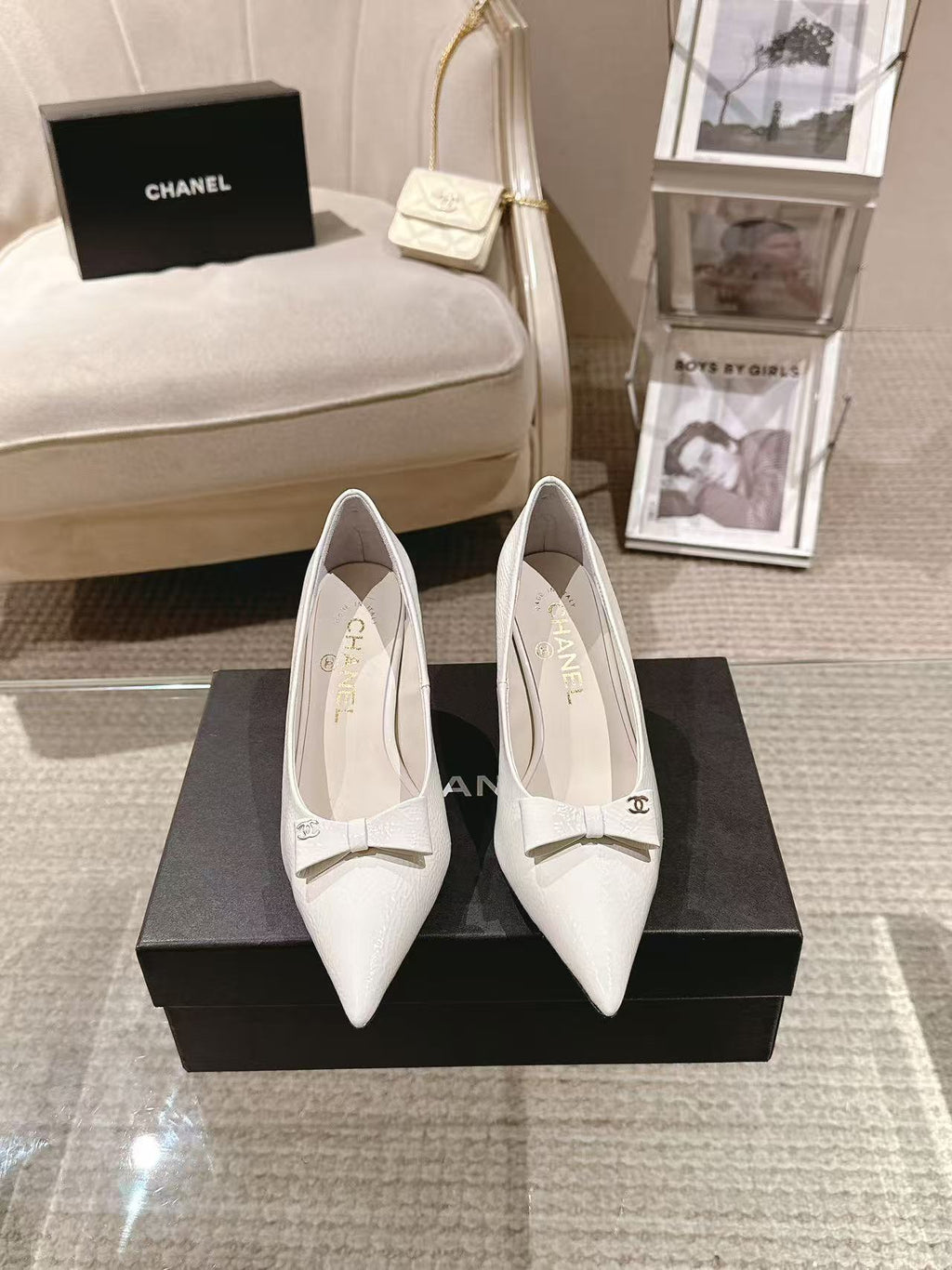 Pair of white pointed-toe slingback heels with bow strap on black display box