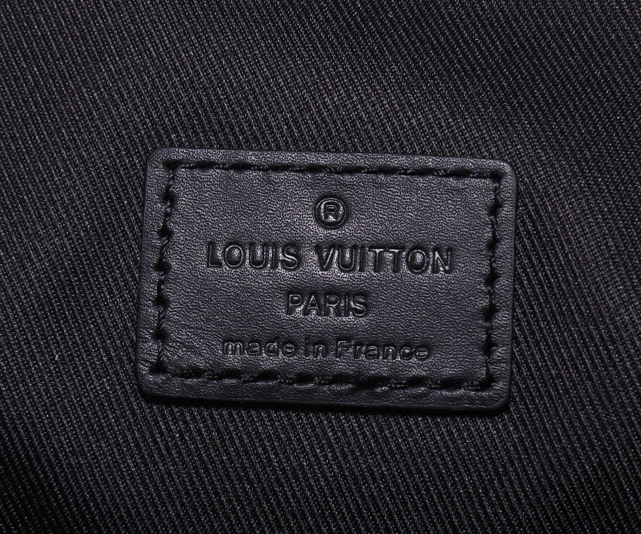 Embroidered logo label on black fabric reading Louis Vuitton Paris