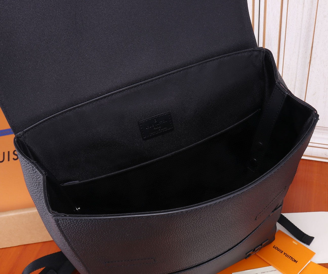 Open black leather bag showing interior lining and small logo patch